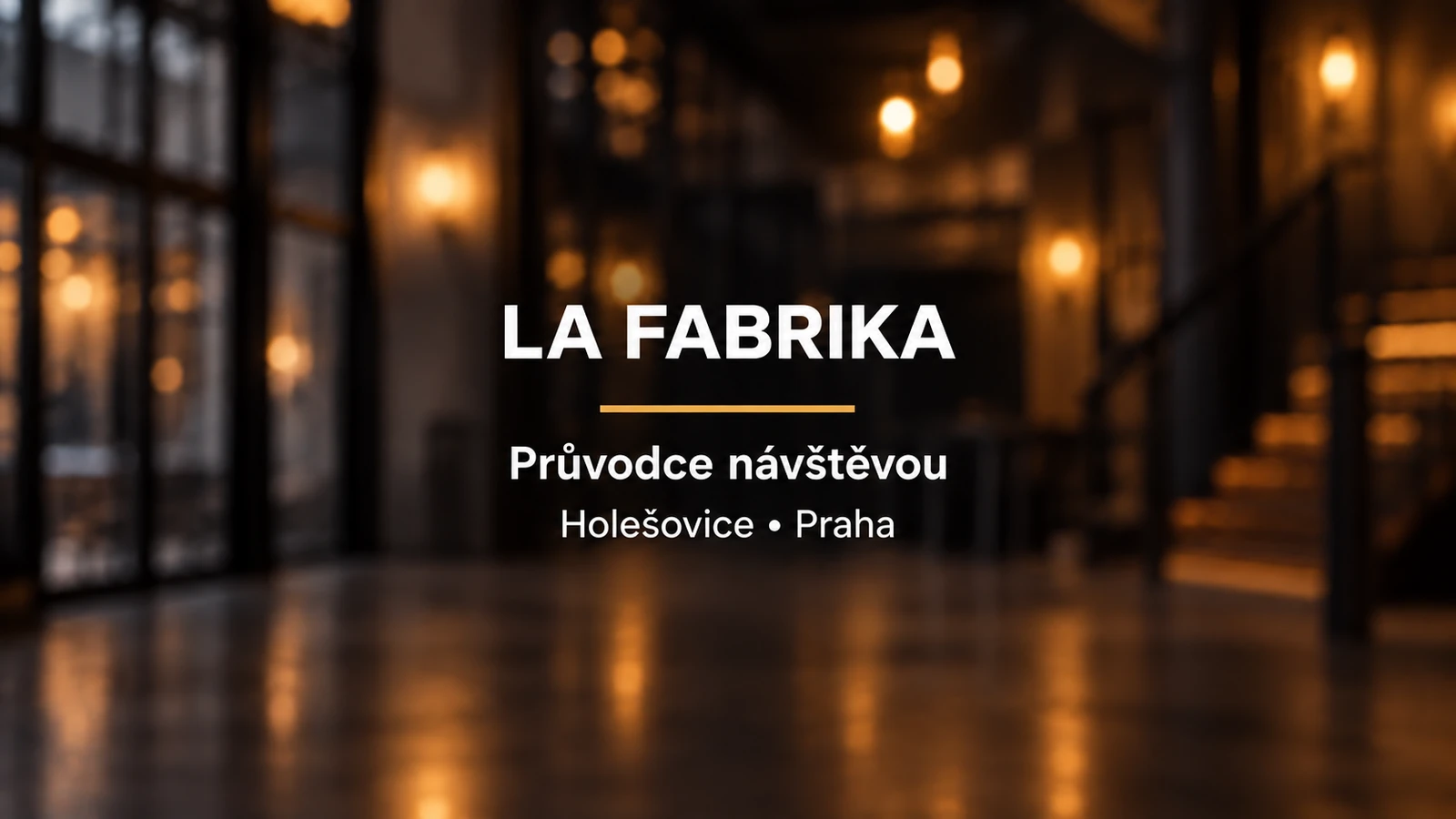 La Fabrika: bílý název a zlatá linka na rozostřeném pozadí divadelního foyer
